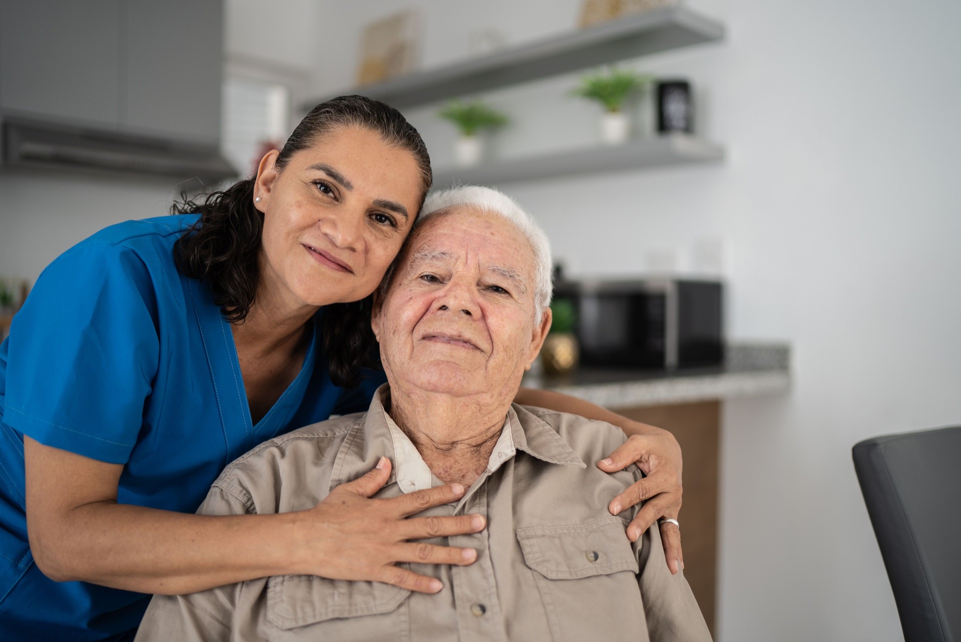 Portrait of nurse embracing senior man at home